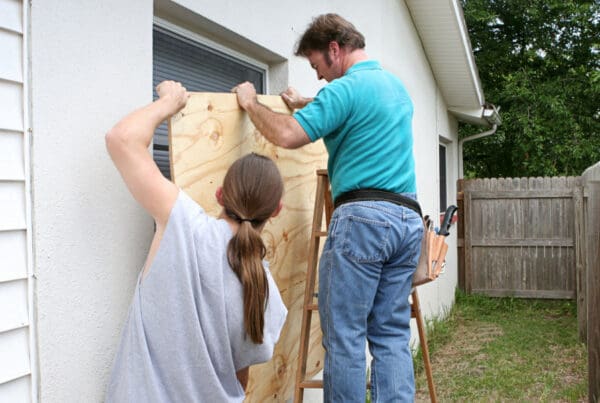Two homeowners secure plywood over a window as they prepare their home for an approaching hurricane or severe storm in Connecticut.