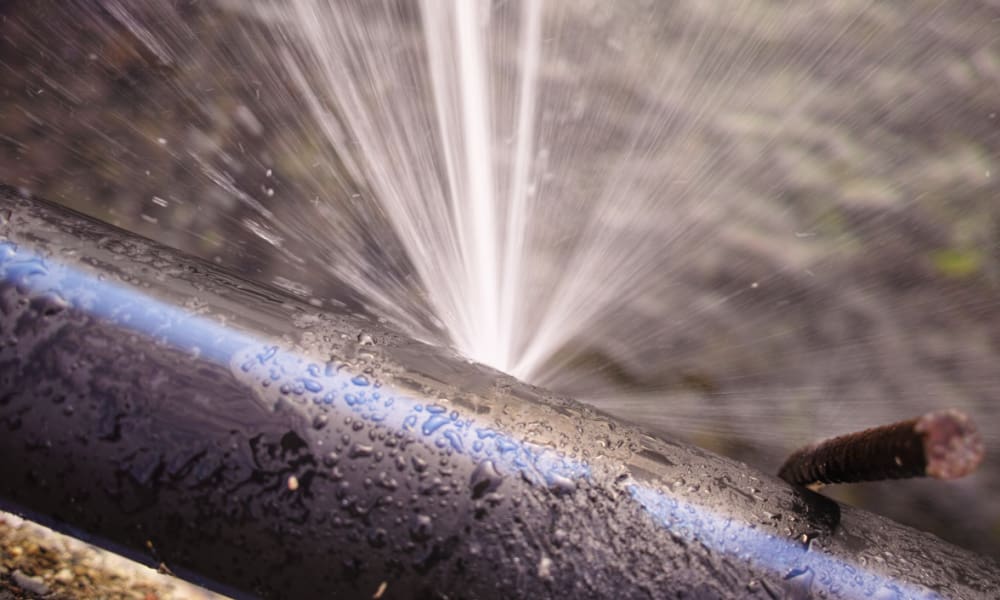 4 Water Damage Situations Standard Home Insurance Policies Won’t Cover. Pipe in ground bursting with water spraying out.