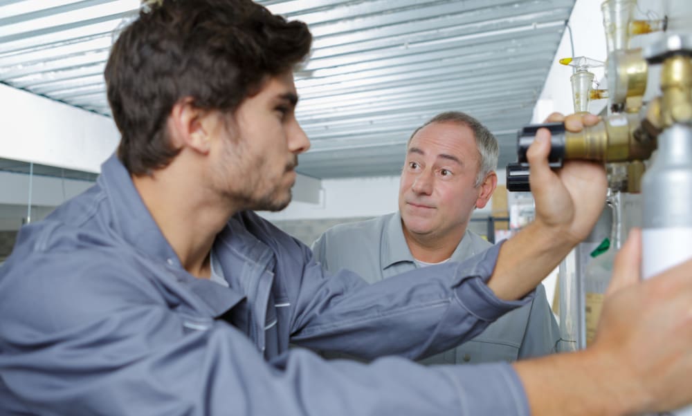Why Should Plumbing Contractors Partner With An Independent Insurance Agent? Plumbing apprentice being taught by owner.