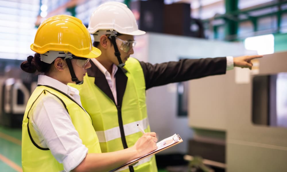 Why Connecticut Manufacturers Can’t Afford to Overlook EPLI Coverage. Male and female employees with hard hats surveying a job.